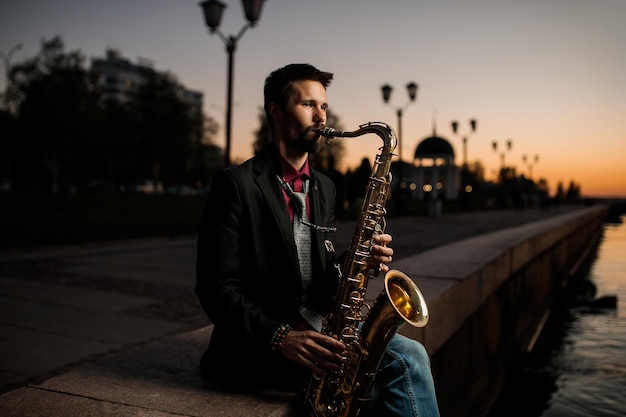 El saxofanista toca por la noche afuera.