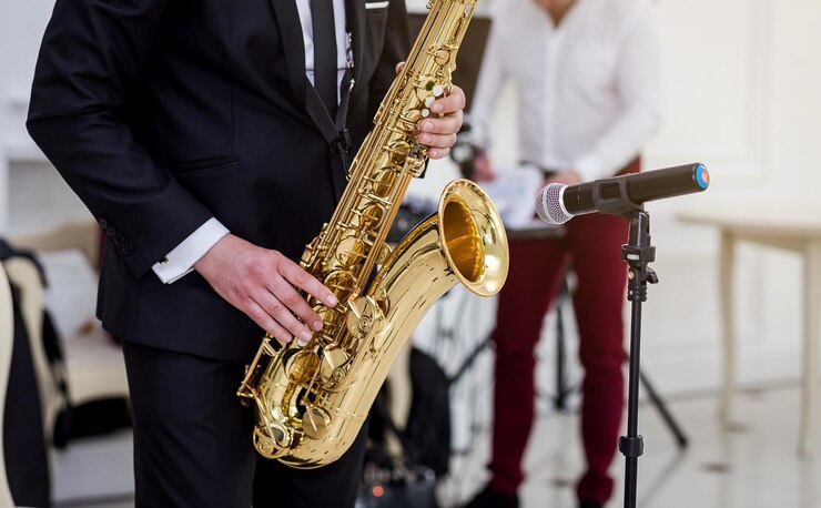 Foto saxofón dorado con motas en manos masculinas