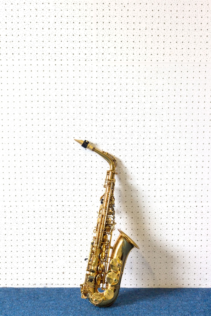 Foto saxofón dorado sobre fondo blanco y azul de la pared