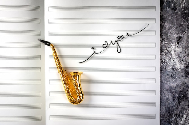 Foto saxofón en el fondo del cuaderno musical con las palabras