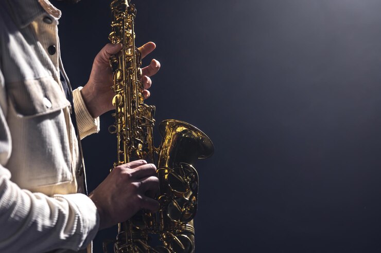 Foto saxofón en manos de un hombre en un espacio de copia de fondo oscuro