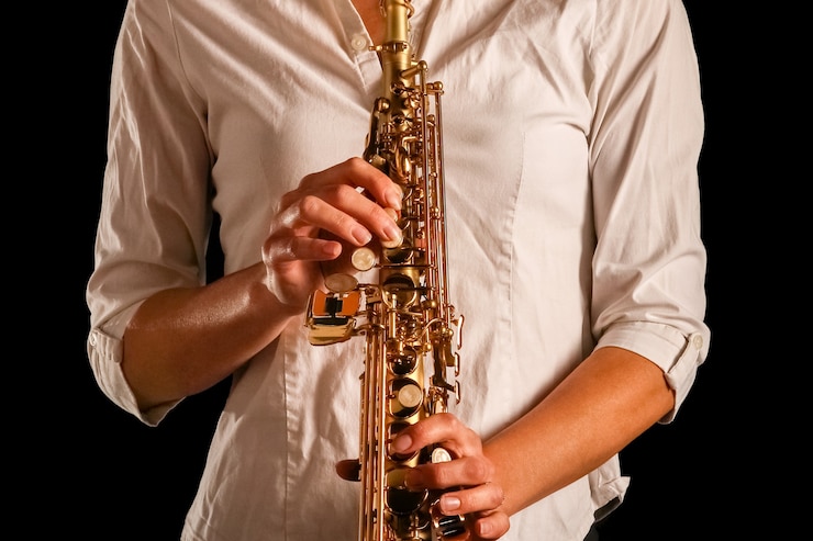 Foto saxofón soprano en manos de una niña sobre una superficie negra