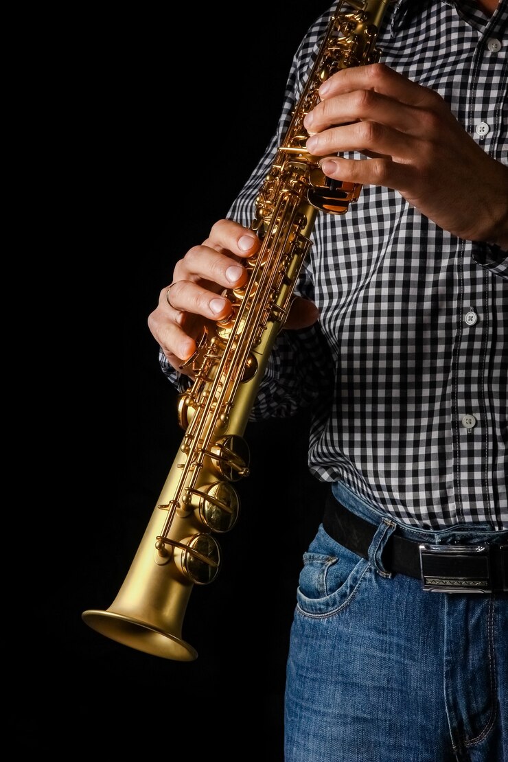 Foto saxofón soprano en manos sobre un fondo negro