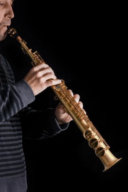 saxofone soprano nas mãos de um cara em um fundo preto