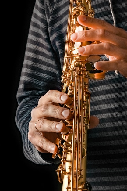 Saxofone soprano nas mãos de um cara em uma superfície preta