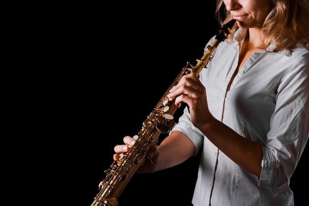 Saxofone soprano nas mãos de uma garota em um fundo preto