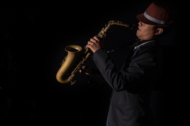 Foto un saxofonista en un fondo oscuro, tono blanco y negro