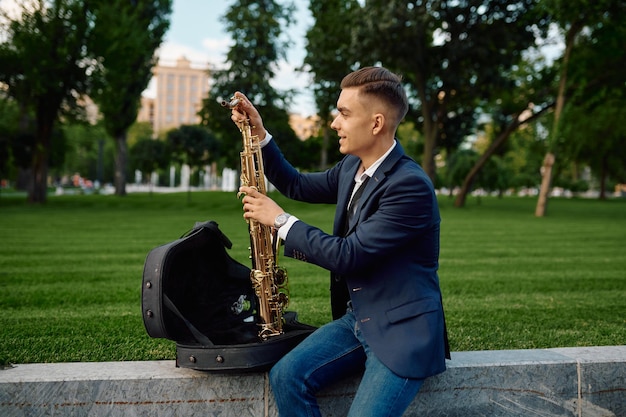 Saxofonista masculino toma el saxofón del estuche