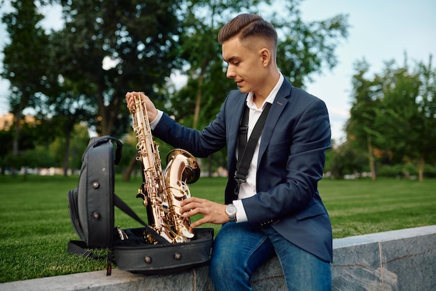 Saxofonista masculino toma el saxofón del estuche