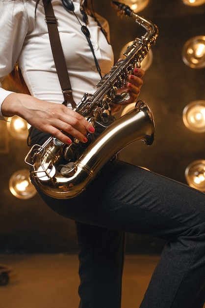 Saxophonistin spielt das Saxophon auf der Bühne mit Scheinwerfern. Jazzmusiker, der auf der Szenenahaufnahme spielt