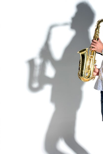 Saxophonistschattenbild-Schattenmann auf weißer Wand.