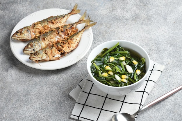 Foto sayur bayam bening ou sopa clara de espinafre com peixe frito definido menu diário fundo branco