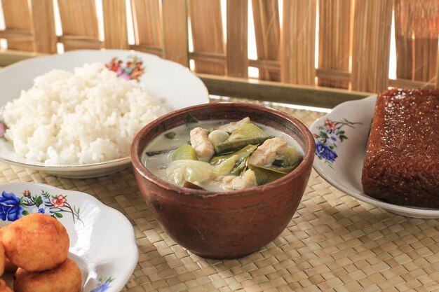 Sayur Lodeh o Sopa de Verduras con Leche de Coco. Comida culinaria tradicional indonesia de Java en un tazón tradicional servido en una mesa de bambú. Enfoque selectivo