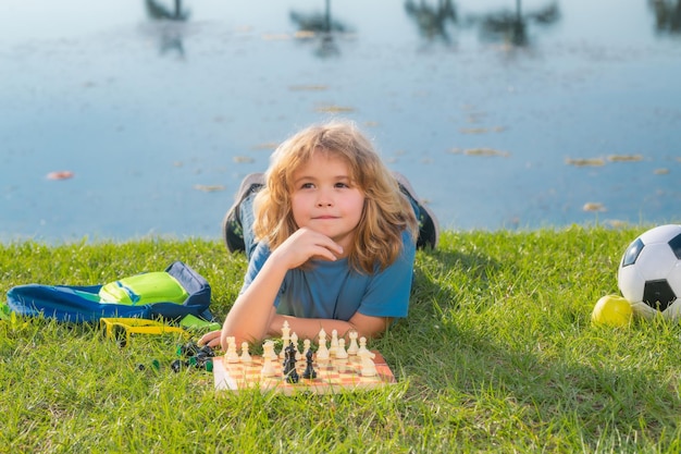 Schachschule im Freien Kind legt sich im Frühlingspark auf Gras und denkt über Schachspiel nach Kindererziehungskonzept Intelligente, intelligente und clevere Schulkinder Traumkinder und Kindheitskonzept