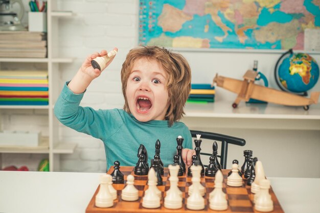 Schachschule Sohn spielt Schach und lächelt zu Hause Kleiner kluger Junge, der an Schach denkt