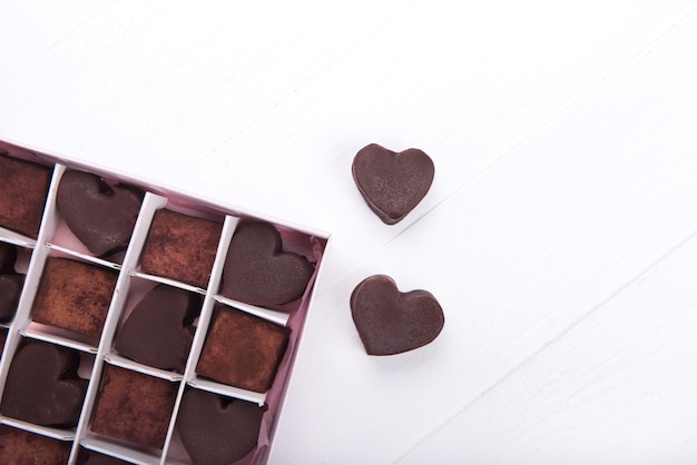 Schachtel mit herzförmigen Schokoladenbonbons auf weißem Hintergrund. Valentinstag Konzept. Speicherplatz kopieren.