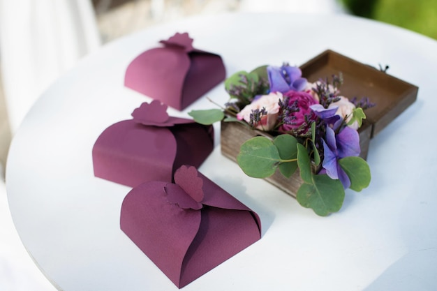 Schachteln mit einem Geschenk für die Gäste einer Hochzeit neben einer Schachtel mit Blumen