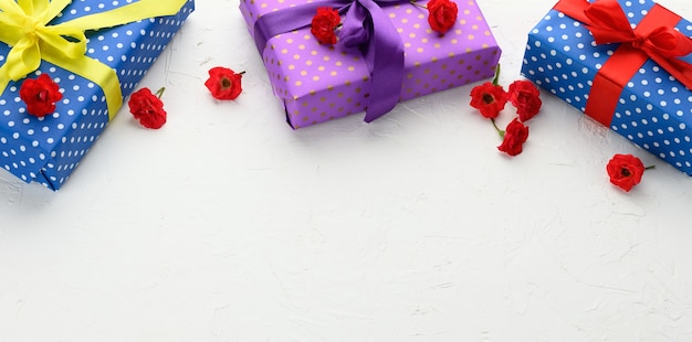 Schachteln sind in Weihnachtspapier mit Tupfen verpackt und mit einem Seidenband auf einem Hintergrund, Geburtstagsgeschenk, Überraschung, Kopienraum gebunden