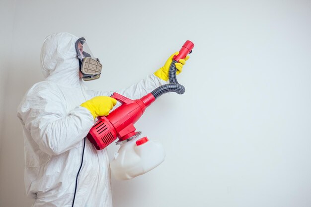 Foto schädlingsbekämpfungsarbeiter, der pestizide mit sprühgerät in der wohnung sprüht, kopieren sie den weißen wandhintergrund.