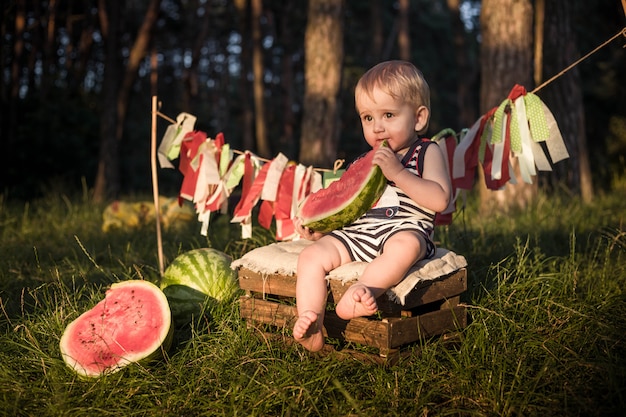 Schätzchenblonder Junge essen Wassermelone und lächeln.