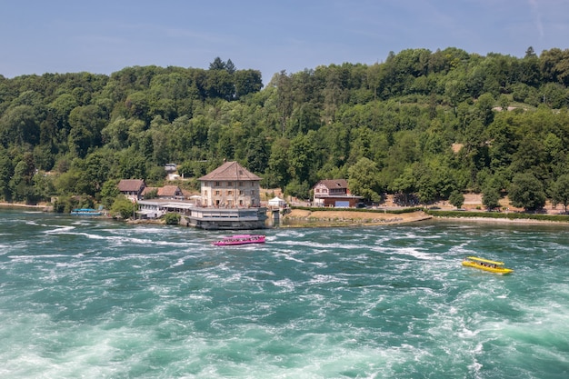 Schaffhausen, Suiza - 22 de junio de 2017: Barco con gente flotando a la cascada de las cataratas del Rin. Es uno de los principales atractivos turísticos. Día de verano con cielo azul
