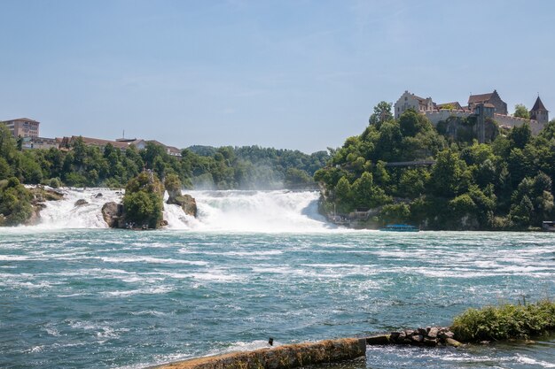 Schaffhausen, Suiza - 22 de junio de 2017: Barco con gente flotando a la cascada de las cataratas del Rin. Es uno de los principales atractivos turísticos. Día de verano con cielo azul