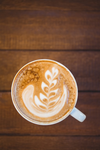 Schale Cappuccino mit Kaffeekunst auf Holztisch