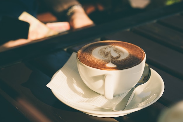 Schale Cappuccino mit Zimt auf einem Holztisch in einem Café