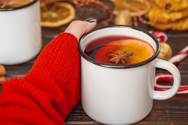 Schale Glühwein in den Händen der Frau auf Holztisch