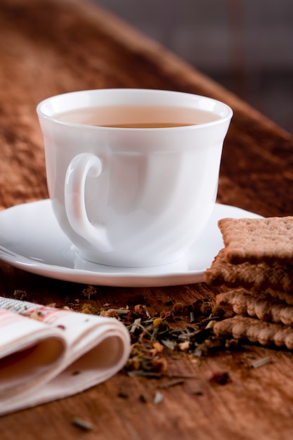 Schale Kräutertee und Nahaufnahme einiger frischer Plätzchen auf Holztisch