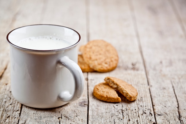 Schale Milch und einige frische gebackene Haferplätzchen auf rustikalem Holztisch