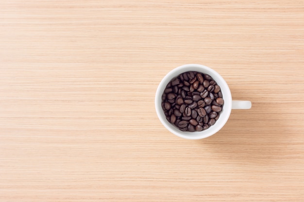 Schale und Kaffeebohnen auf hölzernem Hintergrund mit Kopienraum