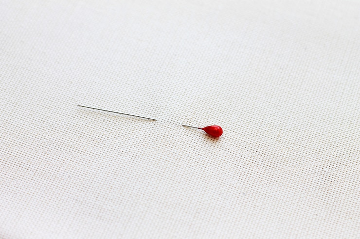 Foto scharfe nadel mit einem roten kopf, der an ein leichtes stoffkonzept aus handarbeit, nähen und kreativität geheftet ist