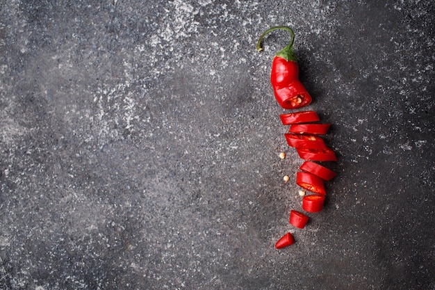 Scharfe rote Paprika auf grauem Hintergrund Chilischote in Stücke geschnitten Platz für Text in einem Lebensmittelfoto