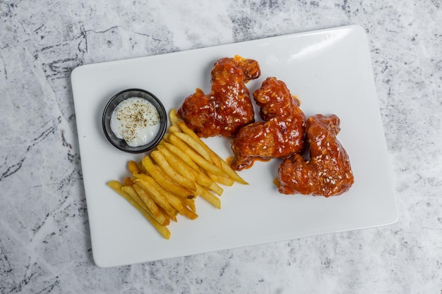 Scharfe und würzige Buffalo Chicken Wings und knusprige Pommes Frites mit weißer Soße