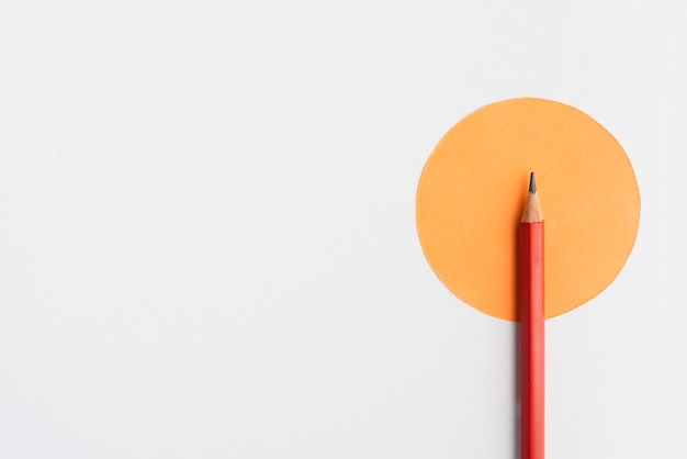 Foto scharfer bleistift auf orange papier der runden form über weißem hintergrund