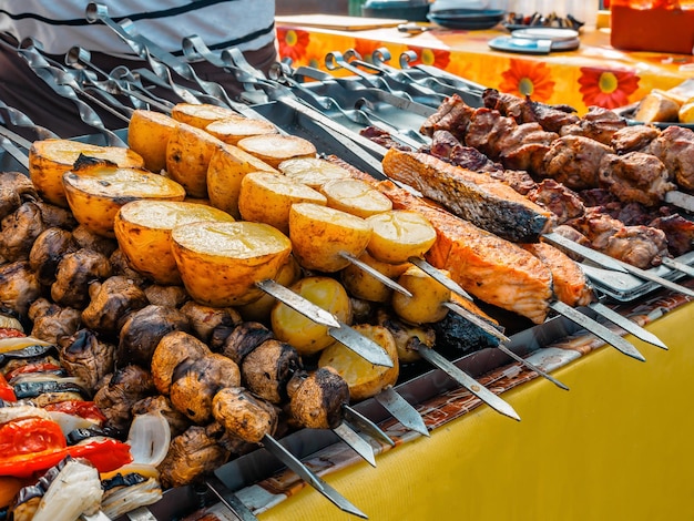 Schaschlik am Metallspieß kochen und gegrilltes Gemüse. Gegrilltes Fleisch und Gemüse. Köstliches Streetfood