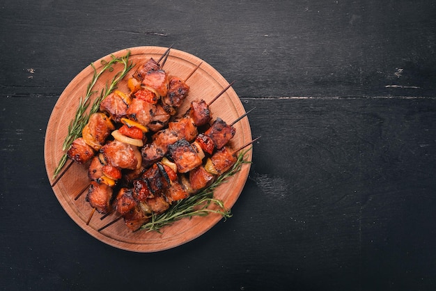 Schaschlik am Spieß mit Zwiebeln auf dem schwarzen Holztisch