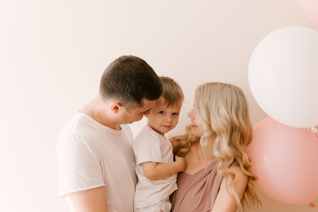 Schastlivaya lächelnde Hunde sind eine junge Familie mit einem Kind mit Luftballons