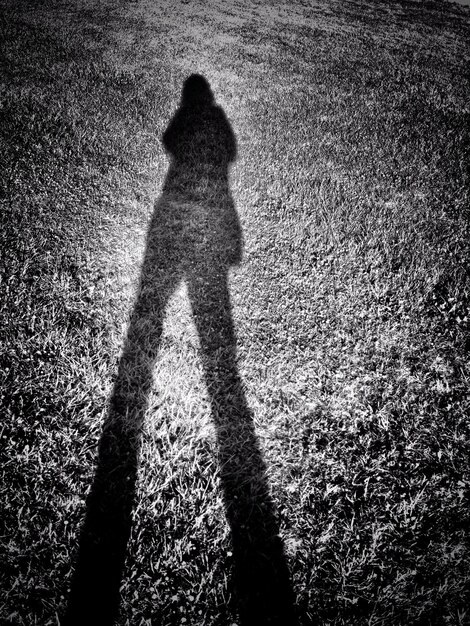 Foto schatten einer frau auf einem grasbewachsenen feld