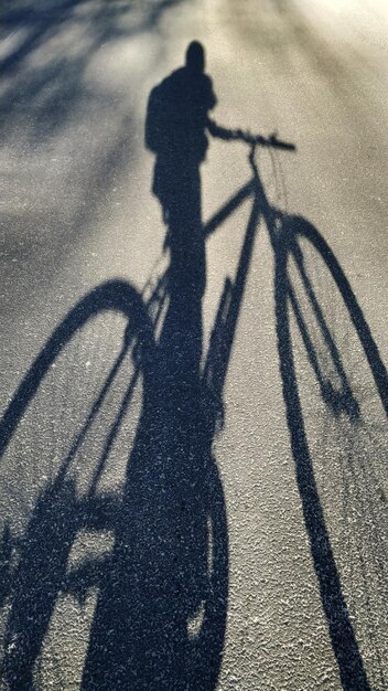 Foto schatten einer person, die fahrrad auf der straße fährt