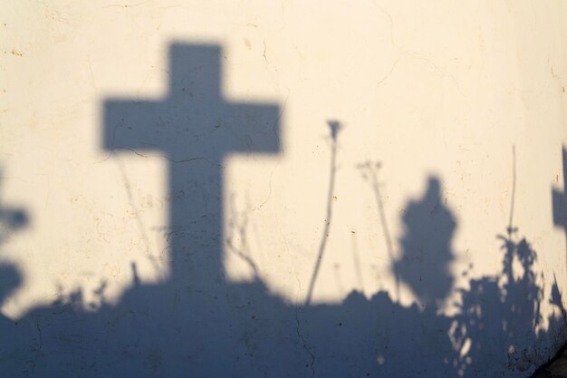 Schatten eines Kreuzes auf einem Grab auf einem griechischen Friedhof im Morgengrauen