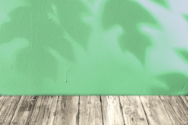 Schatten und Licht der Blätter auf der grünen Zementwand und dem Holzboden