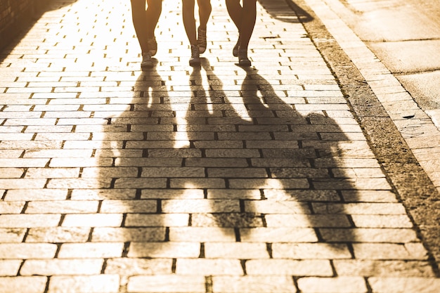 Schatten von drei Mädchen, die auf einen Bürgersteig in der Stadt gehen