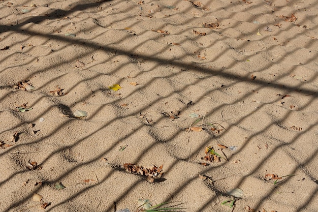 Schatten von einem Gitter auf einem Wellen-Sand-Hintergrund