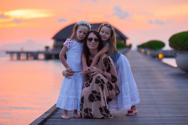 Schattenbild der jungen Mutter und zwei ihrer kleinen Mädchen bei Sonnenuntergang