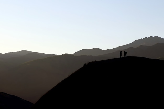 Schattenbild der Leute, die auf dem Hügel stehen
