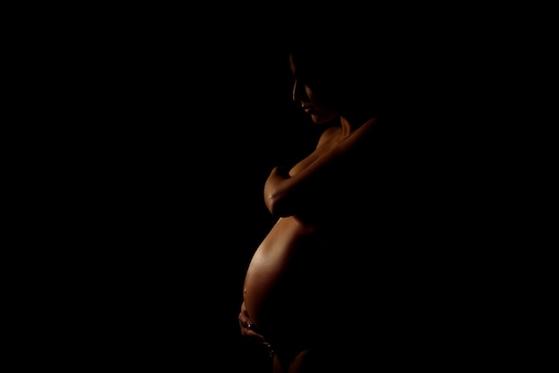 Schattenbild der schwangeren Frau in der Dunkelheit