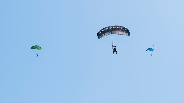 Schattenbild des Fallschirmspringers, der im blauen klaren Himmel fliegt