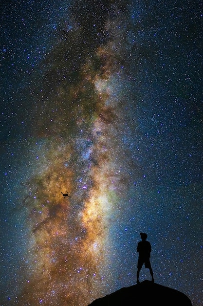 Schattenbild des Fotografen mit Brummen über der Milchstraße auf dem bewölkten Himmel